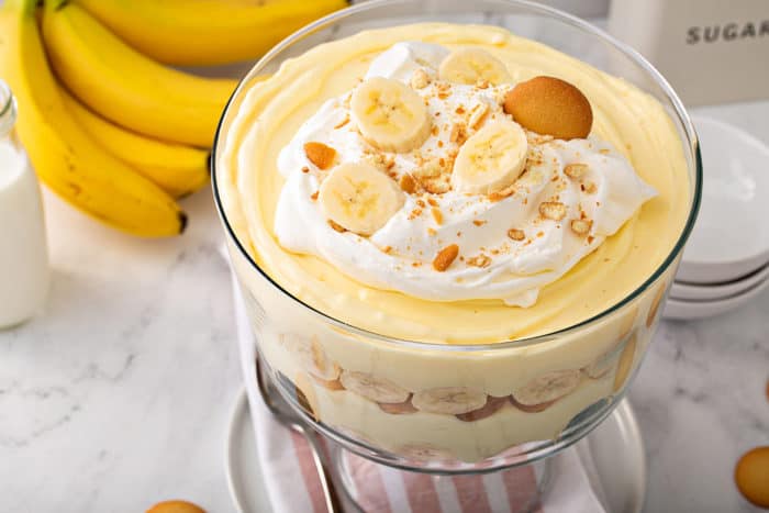 Banana pudding in a trifle dish, topped with whipped cream, bananas, and nilla wafer cookies