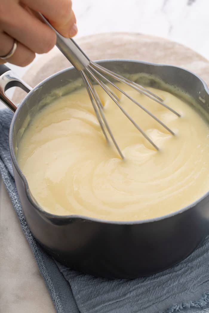 Whisk stirring homemade vanilla pudding in a saucepan