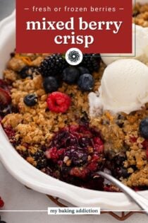 Serving spoon in a white baking dish filled with berry crisp topped with vanilla ice cream. Text overlay includes recipe name.