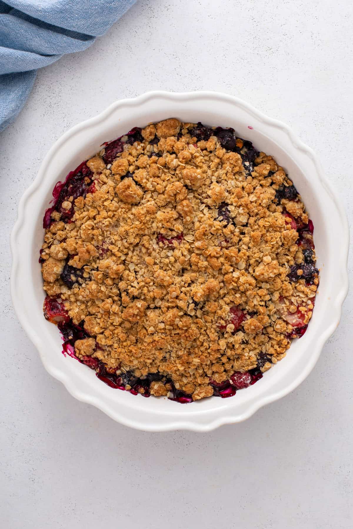 Baked berry crisp in a white baking dish.