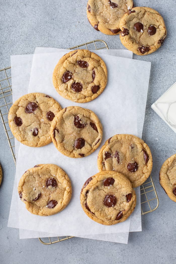 Baked brown butter chocolate chip cookies on a piece of parchment paper set on a wire cooling rack