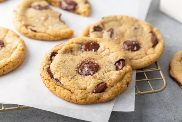 Baked brown butter chocolate chip cookie set on a piece of parchment paper on a wire rack