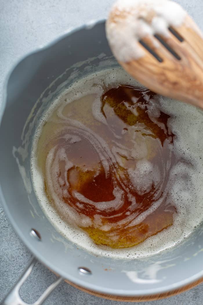 Brown butter in a saucepan, with a wooden spoon set on the edge of the pan
