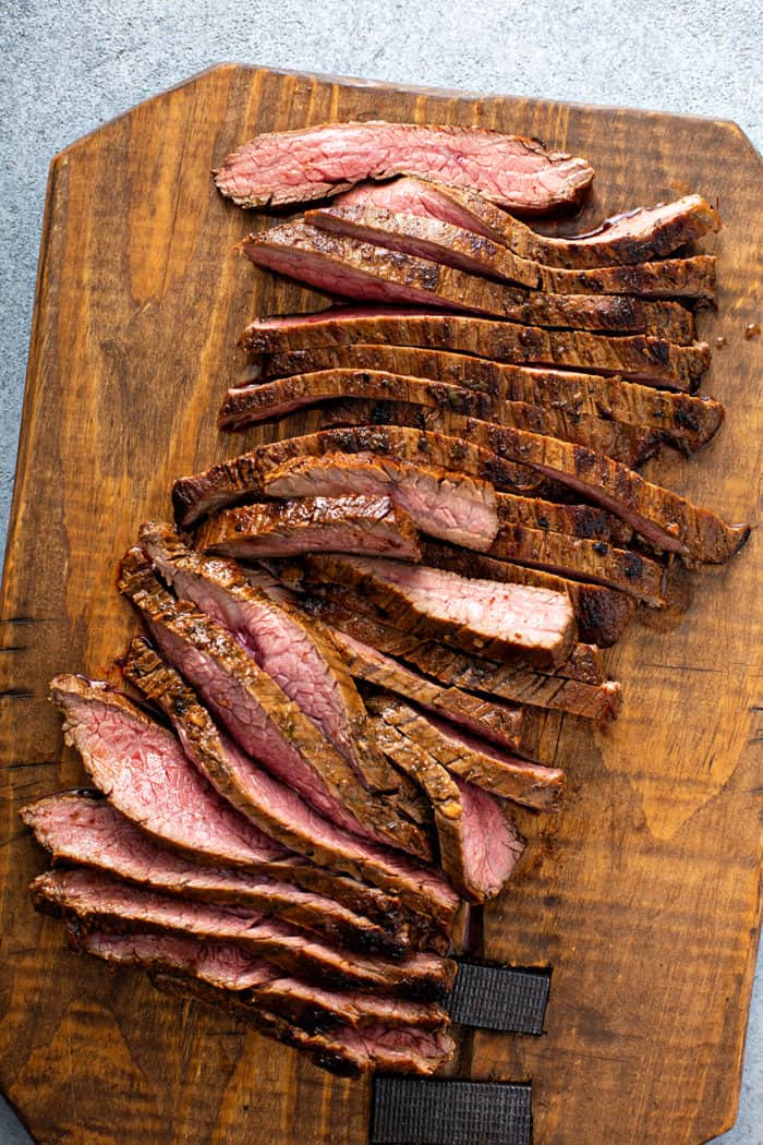 Sliced, grilled flank steak on a wooden cutting board