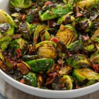Air fried brussels sprouts tossed with bacon and balsamic in a white serving bowl