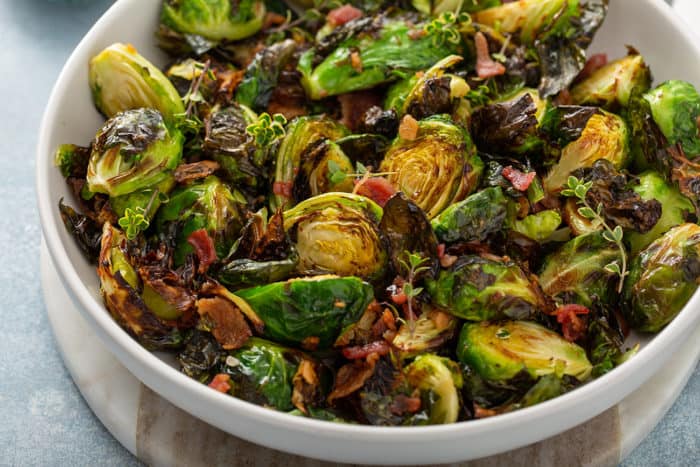 Air fried brussels sprouts tossed with bacon and balsamic in a white serving bowl