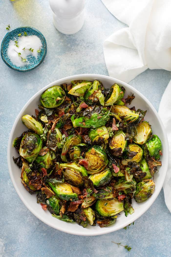 Overhead view of air fryer brussels sprouts in a white serving bowl on a blue counter