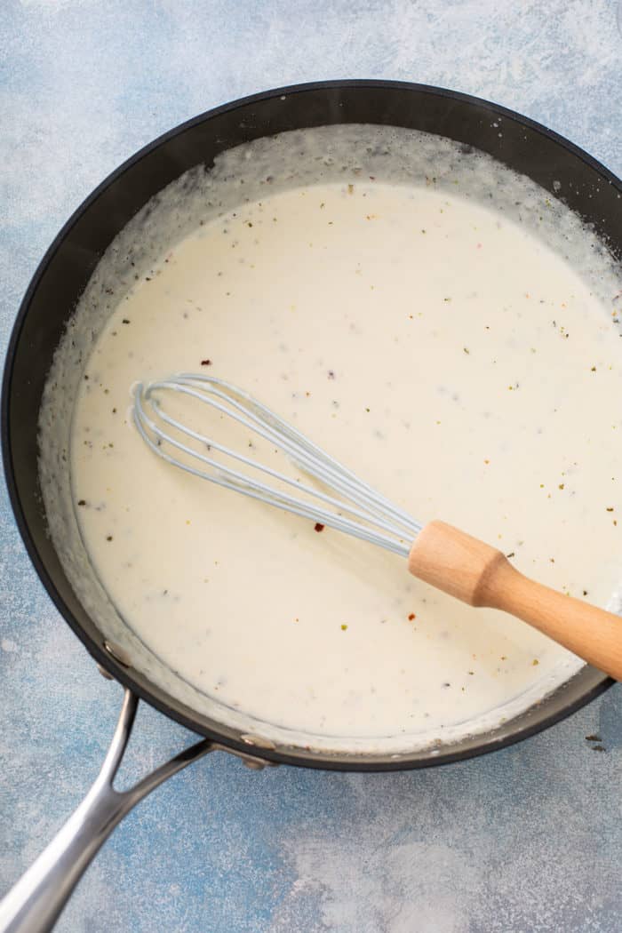 Easy fettuccine alfredo sauce being whisked in a large skillet