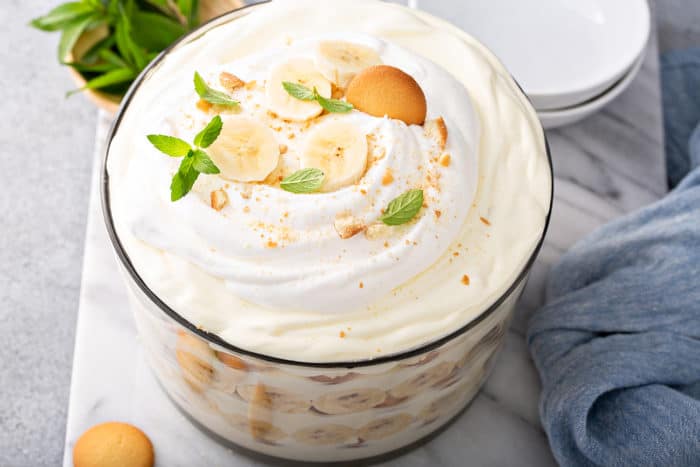 Overhead view of Magnolia Banana Pudding in a trifle dish, garnished with whipped cream, slices of banana, and vanilla wafer cookies