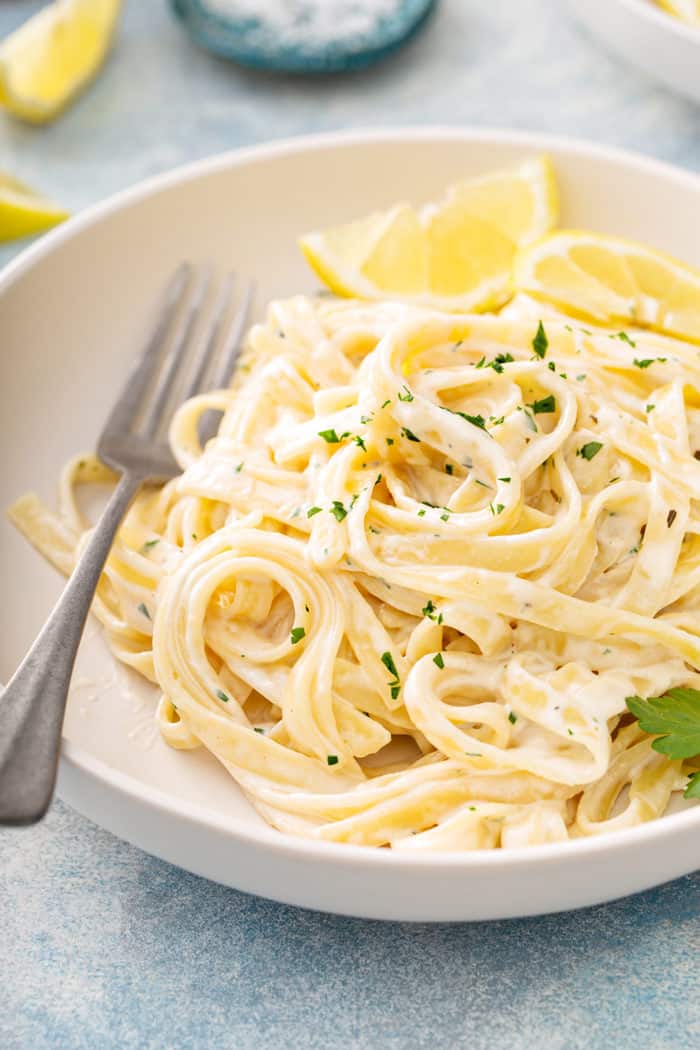 Fork in a bowl of easy fettuccine alfredo set on a white counter