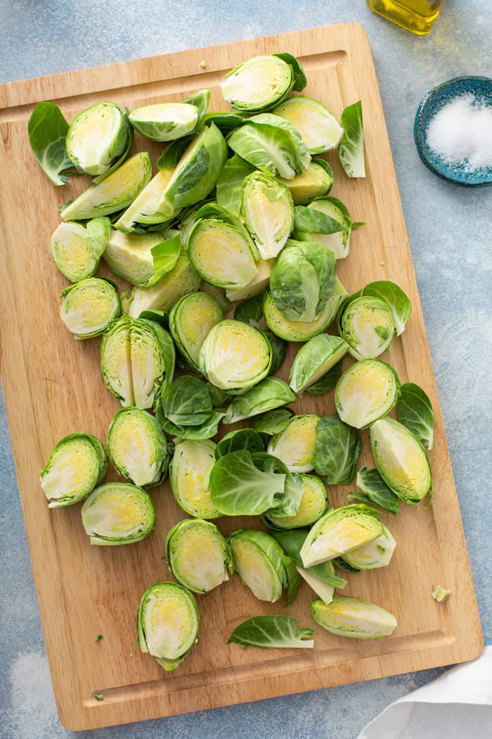 Brussels sprouts sliced in halves and quarters on a wooden cutting board