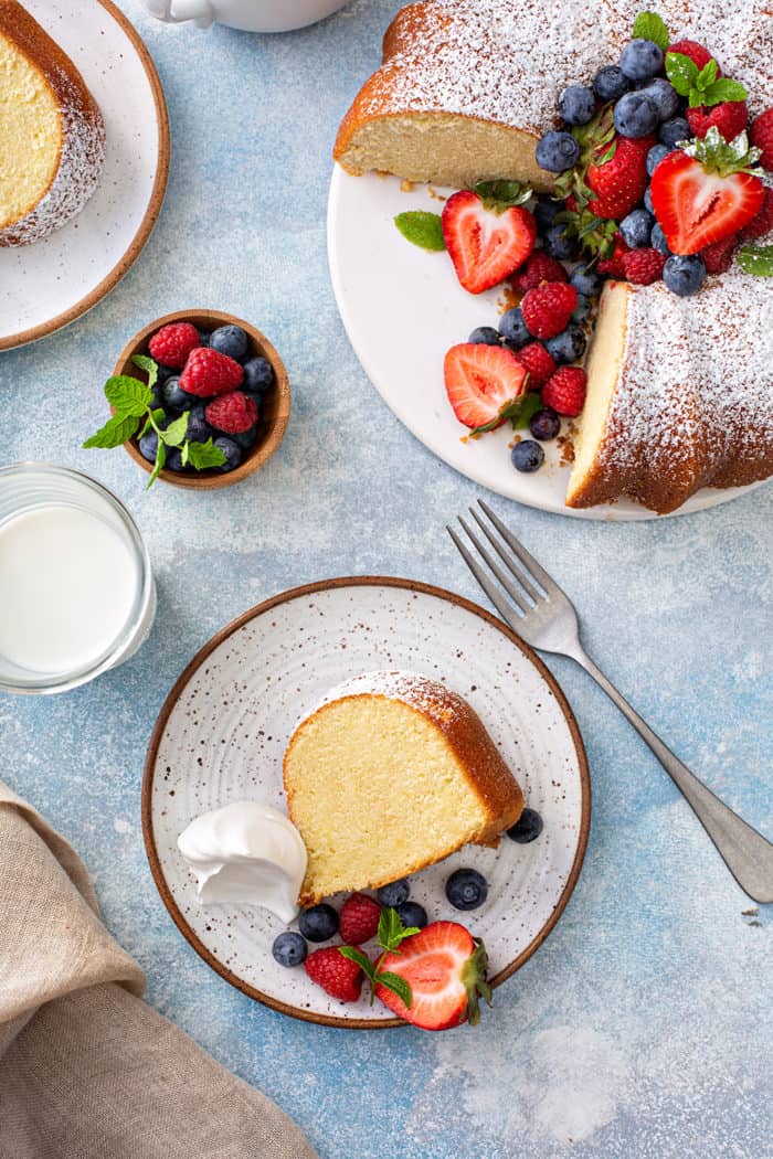 Overhead view of a plated slice of whipping cream cake next to sliced whipping cream cake on a cake plate