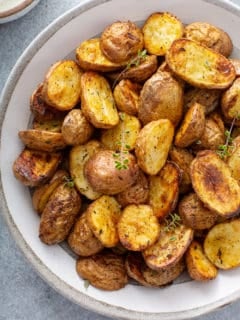Overhead close up view of air fryer roasted potatoes in a white serving bowl