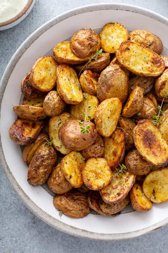 Overhead close up view of air fryer roasted potatoes in a white serving bowl