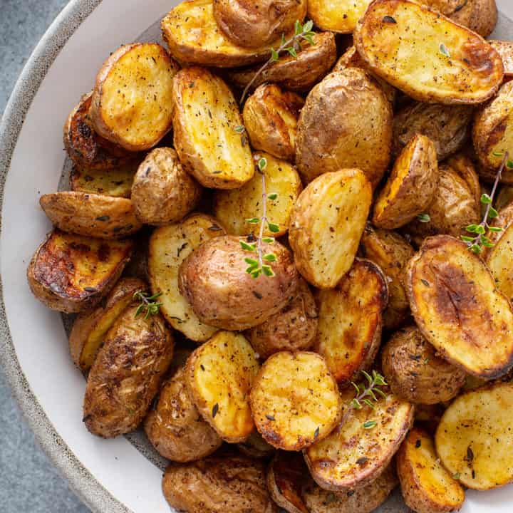 Overhead close up view of air fryer roasted potatoes in a white serving bowl