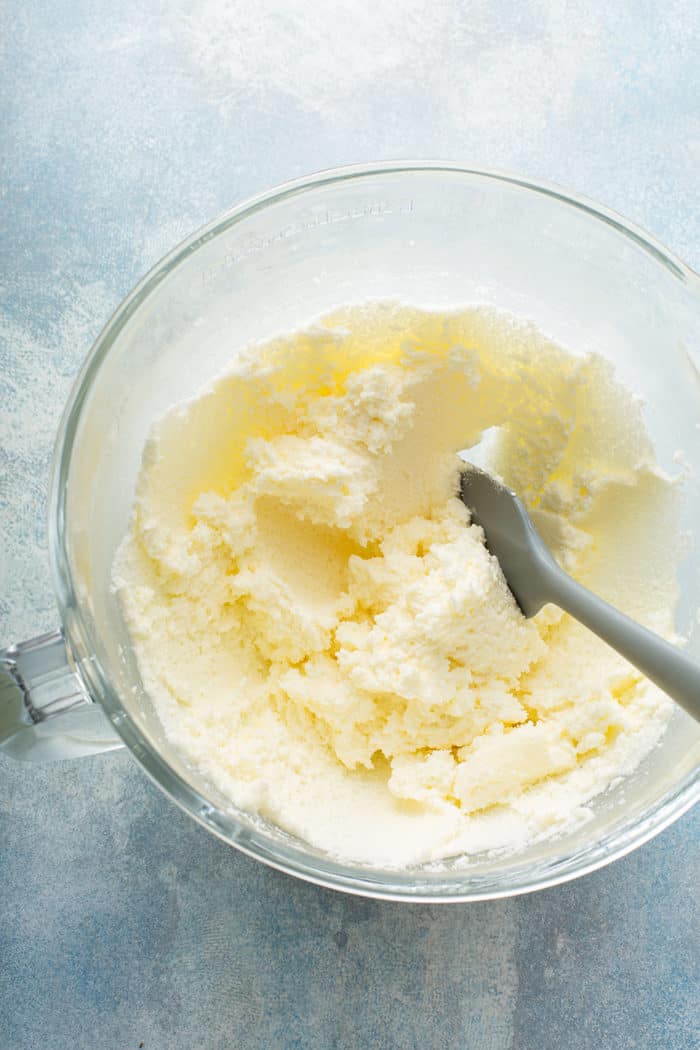 Butter and sugar creamed together in a glass mixing bowl on a blue countertop