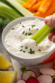Celery stick being dipped into a bowl of homemade ranch dip