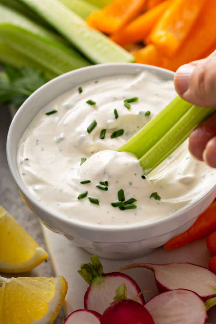 Palito de apio sumergido en un tazón de salsa casera ranch