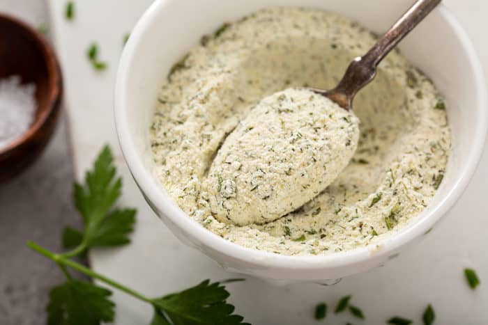 Spoon lifting out a spoonful of ranch seasoning from a bowl of seasoning mix