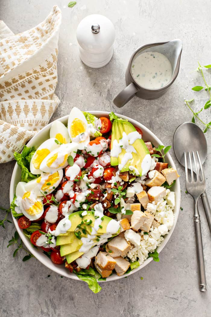 Overhead view of a cobb salad topped with ranch dressing on a gray countertop