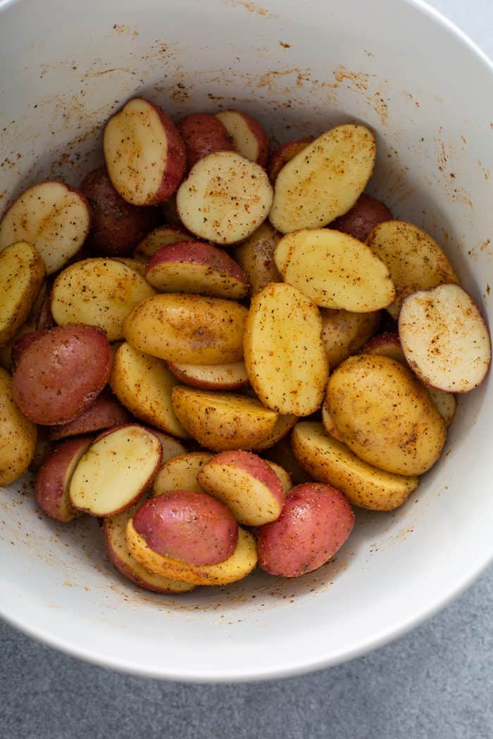 Bowl of seasoned halved potatoes, ready to go into the air fryer