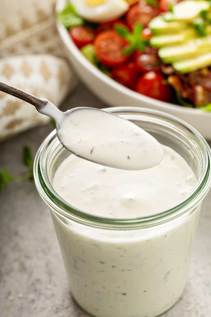 Spoon lifting a spoonful of ranch dressing out of a jar of dressing