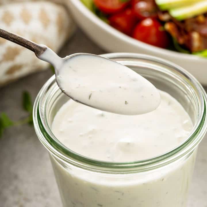 Spoon lifting a spoonful of ranch dressing out of a jar of dressing