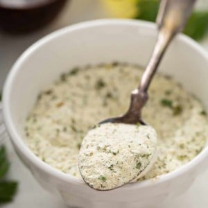 Spoonful of ranch seasoning mix balanced on the side of a bowl of seasoning