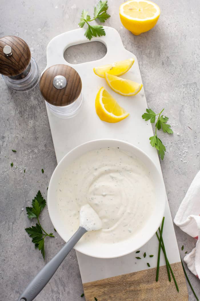 Ranch dip being stirred together with a spatula on a gray countertop