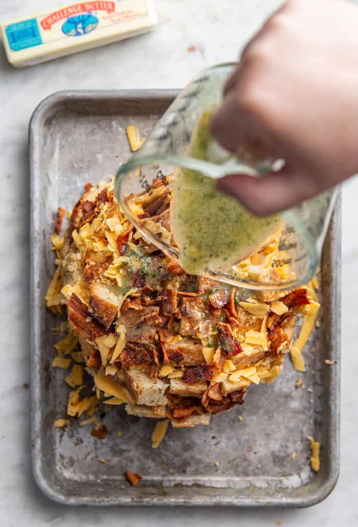 Ranch butter being poured over cheddar bacon pull-apart bread