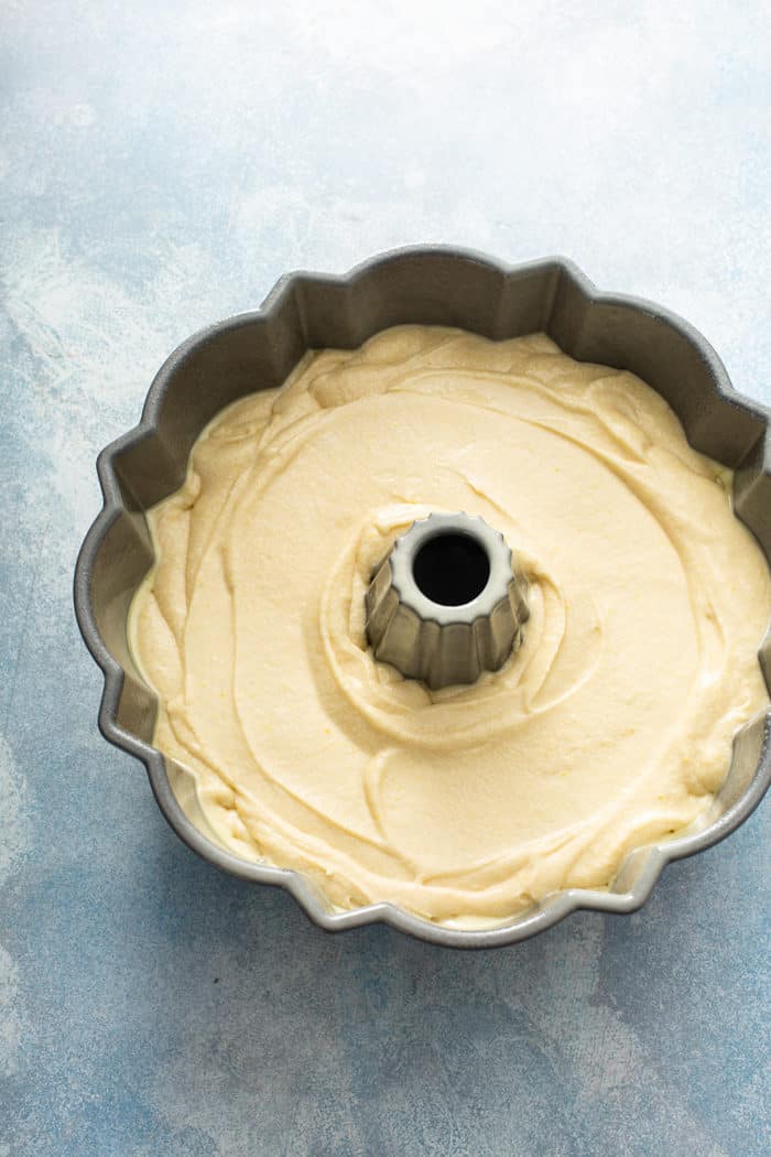 Batter for whipping cream cake in a bundt pan on a blue countertop, ready to bake