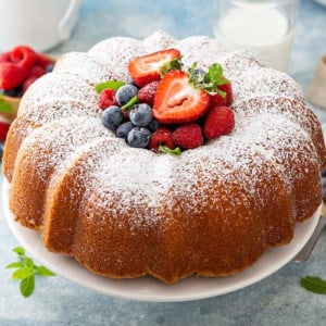 Baked whipping cream cake on a cake plate, with fresh berries piled in the center of the cake