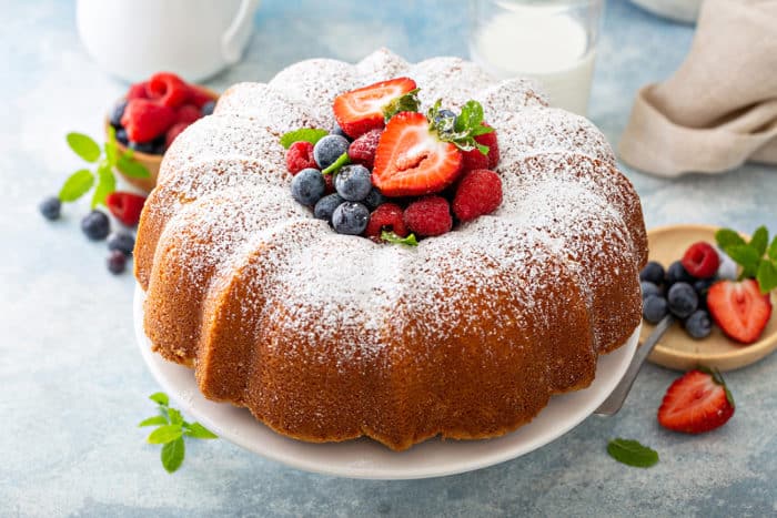 Baked whipping cream cake on a cake plate, with fresh berries piled in the center of the cake