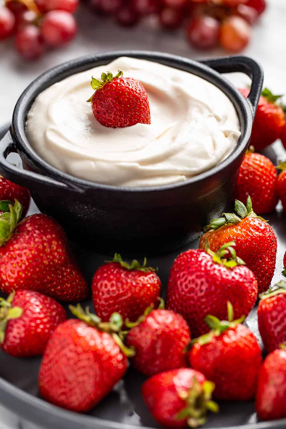 Close up of fruit dip in a serving bowl surrounded by whole strawberries