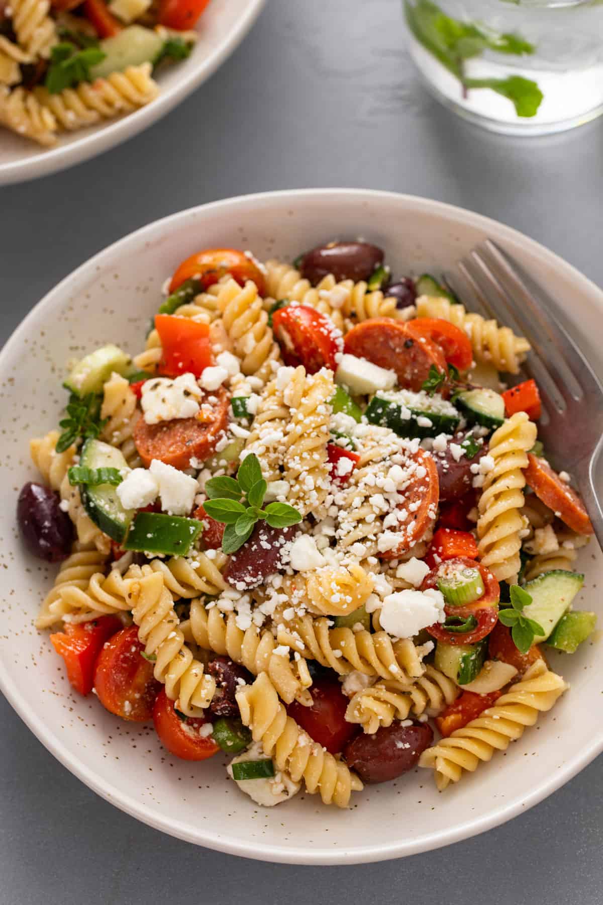 Close up view of greek pasta salad in a white bowl.