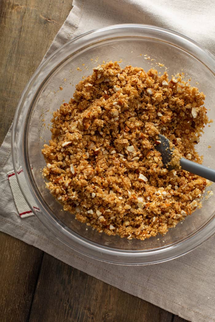 Spoon stirring together the ingredients for a pretzel and graham cracker pie crust in a glass mixing bowl