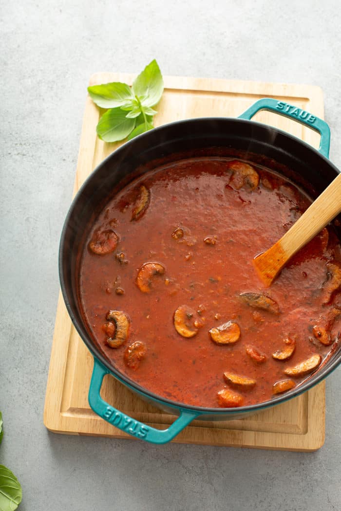 Wooden spoon stirring the sauce for one-pot spaghetti in a large dutch oven