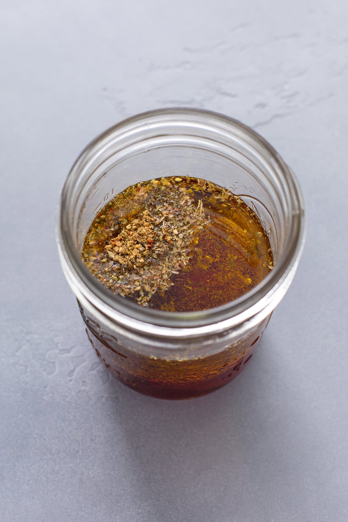 greek salad dressing ingredients added to a mason jar.