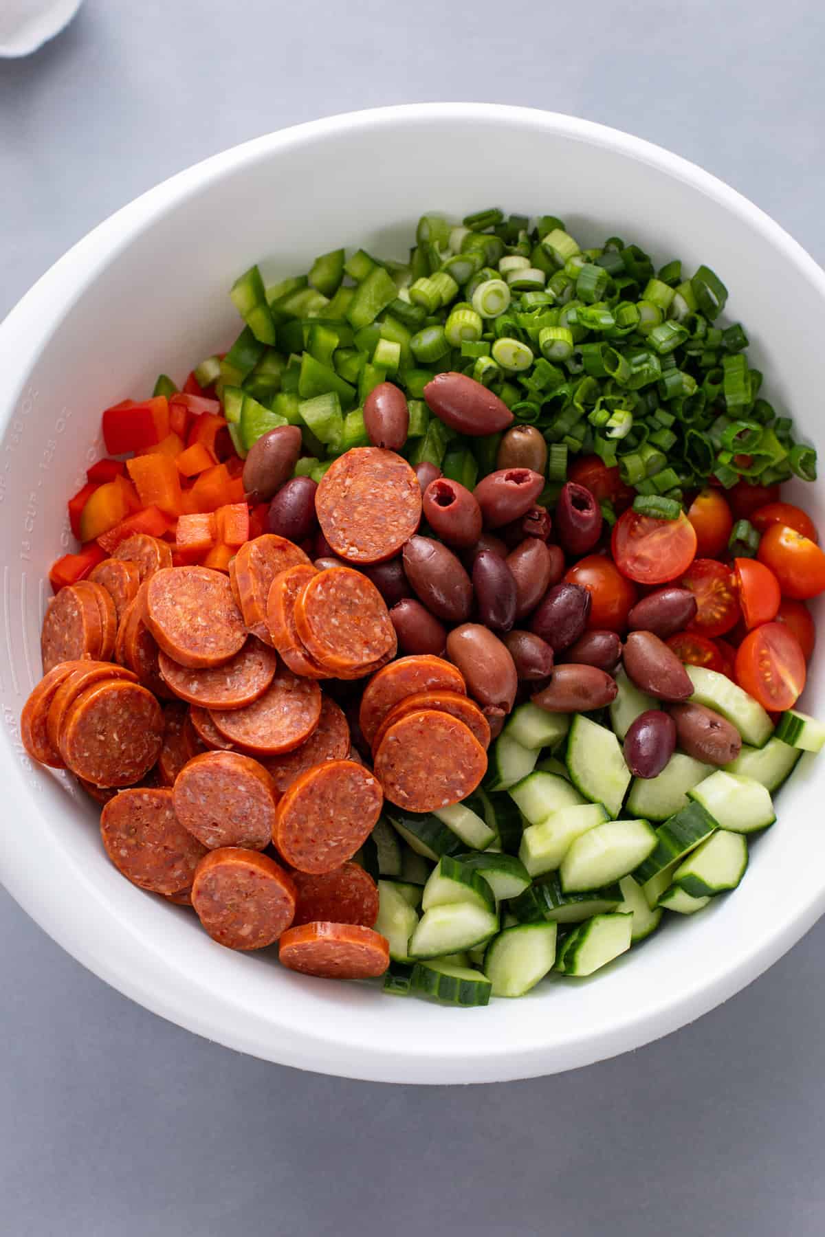 Ingredients for greek pasta salad added to a large mixing bowl.