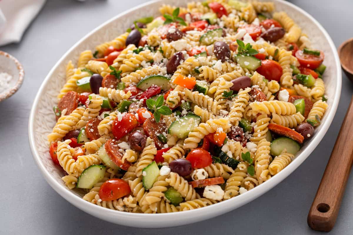 Greek pasta salad in a large oval serving bowl.