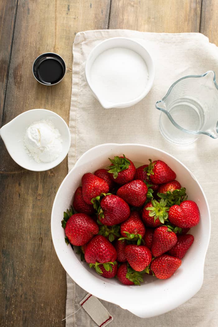 Ingredients for fresh strawberry pie filling arranged on a wooden table