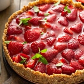 Gros plan d'une tarte aux fraises fraîches, assemblée et décorée de feuilles de menthe