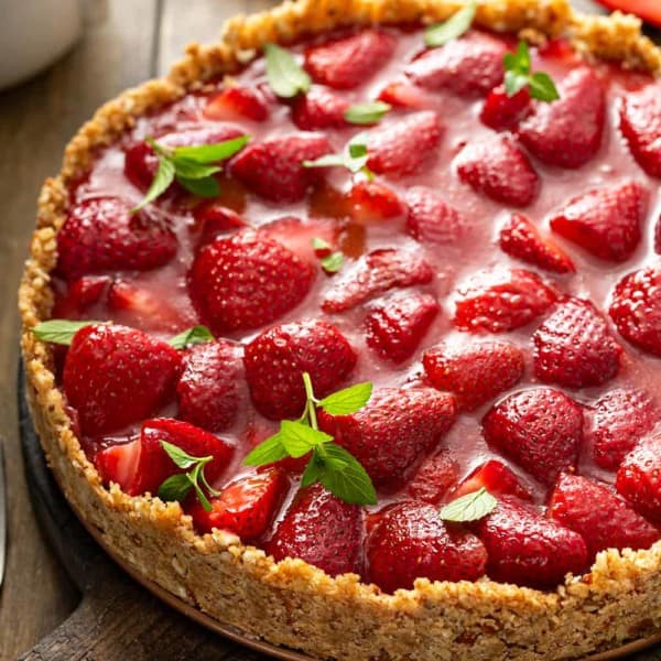 Close up of an assembled and set fresh strawberry pie garnished with mint leaves