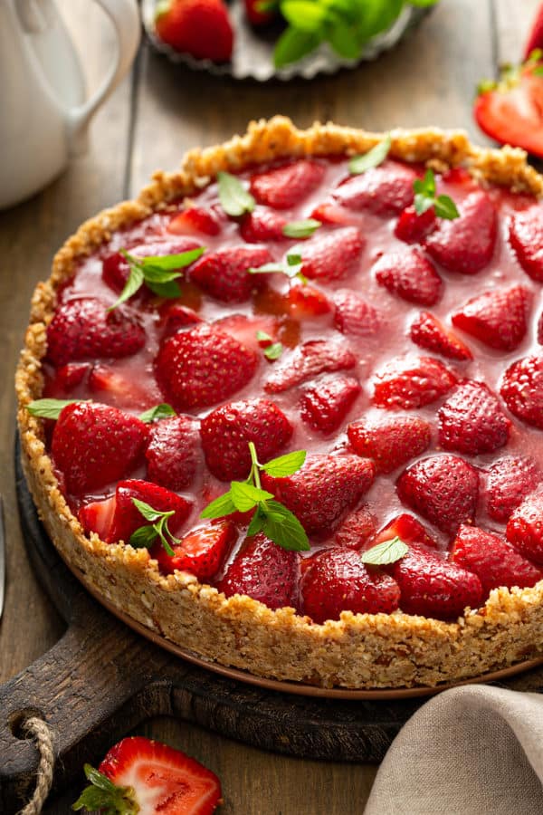Close up of an assembled and set fresh strawberry pie garnished with mint leaves