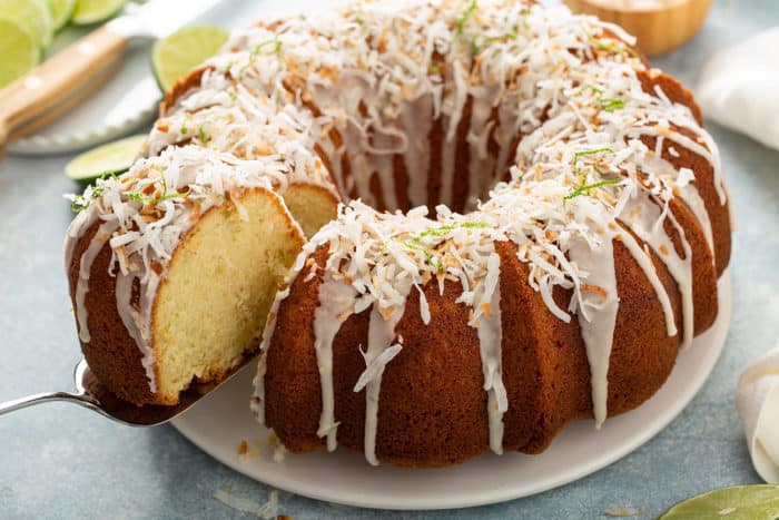 Cake server pulling a slice of lime coconut cake out of the cake