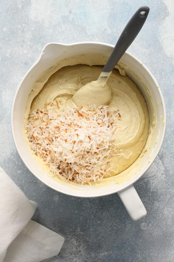 Spatula about to fold toasted coconut into lime coconut cake batter