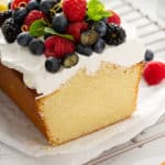 Cross view of sliced lemon whipping cream cake, topped with whipped cream and berries