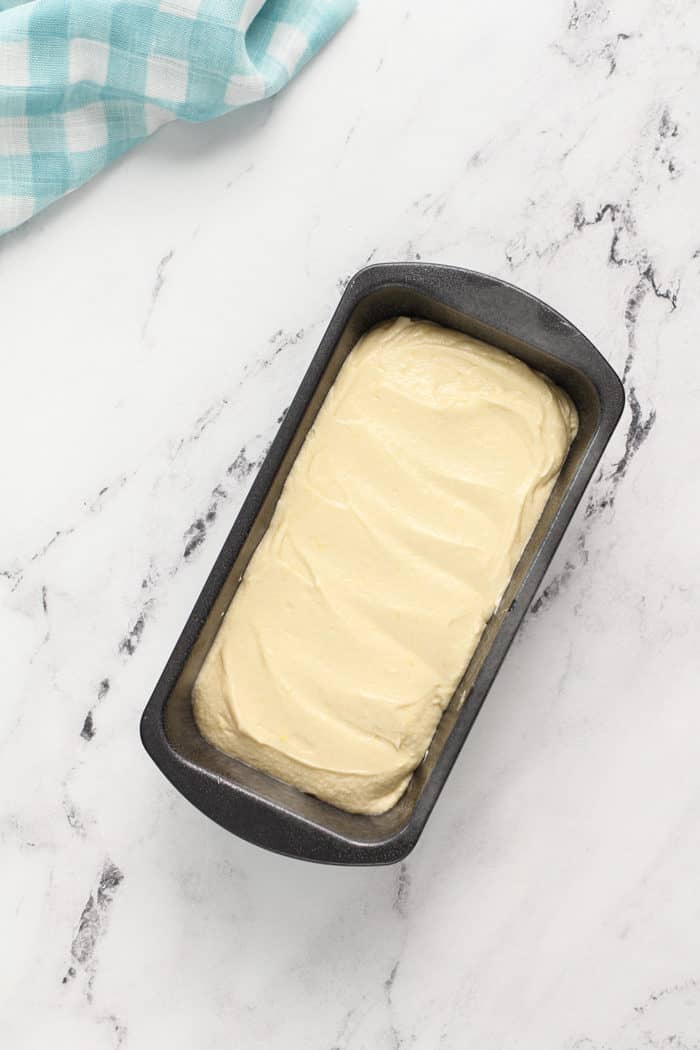 Batter for lemon whipping cream cake in a prepared loaf pan, ready to bake