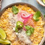 Close up of Mexican street corn salad topped with lime, cotija cheese, cilantro and pickled onions