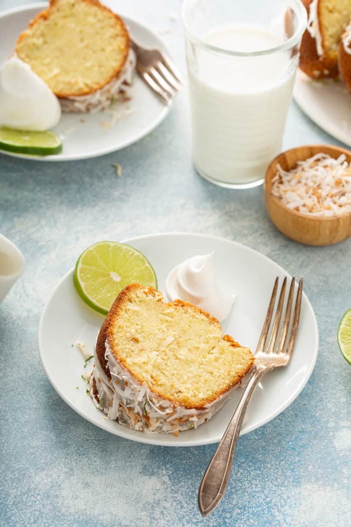 Two white plates with slices of lime coconut cake next to a glass of milk